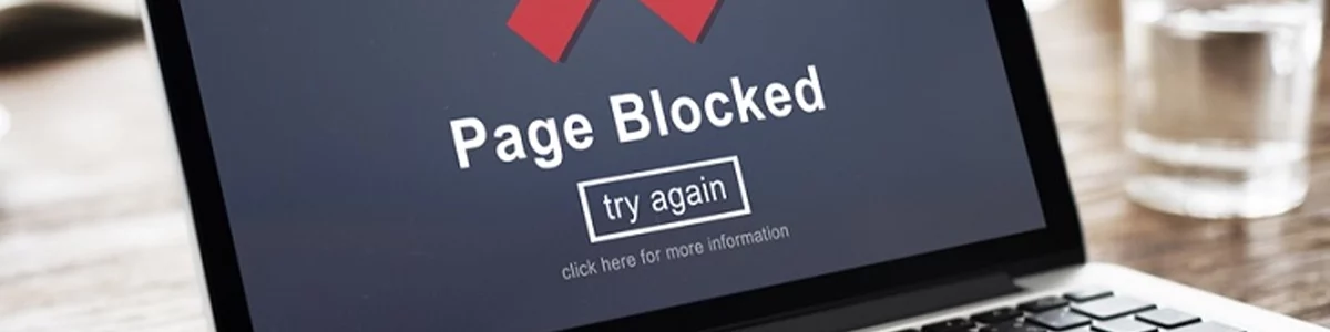 A laptop screen with the words "page blocked" and a red cross