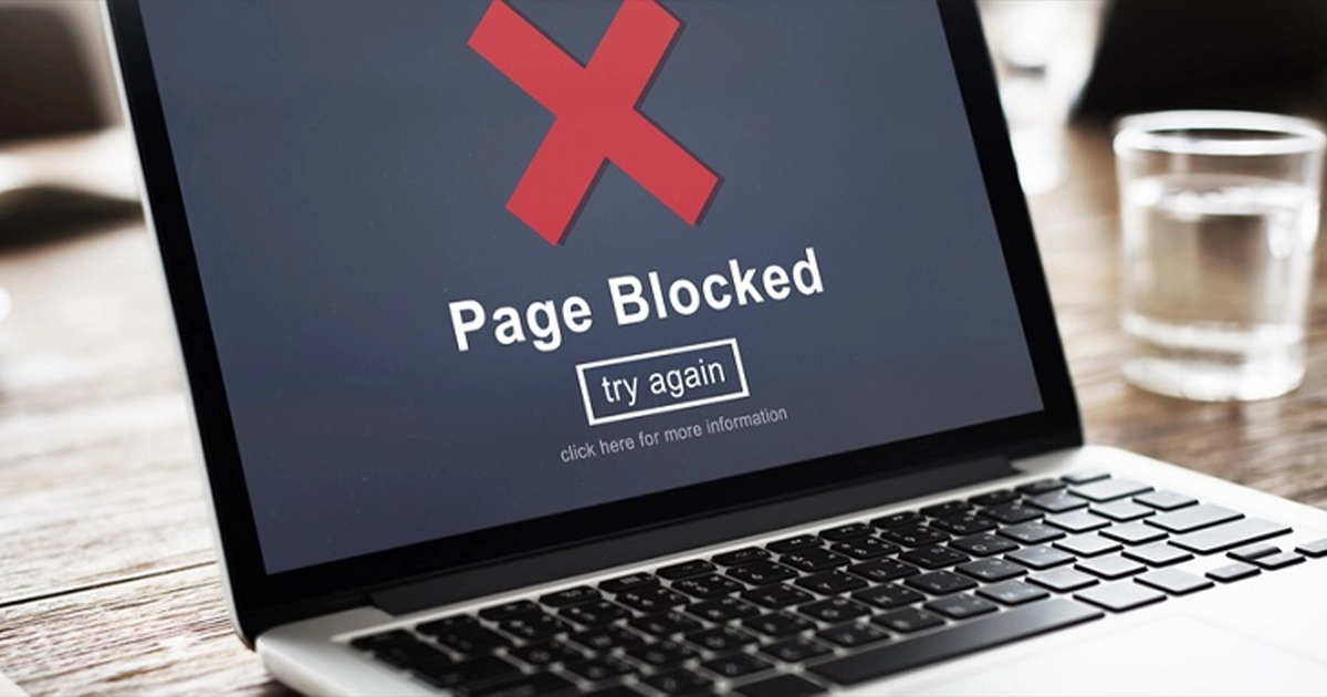 A laptop screen with the words "page blocked" and a red cross