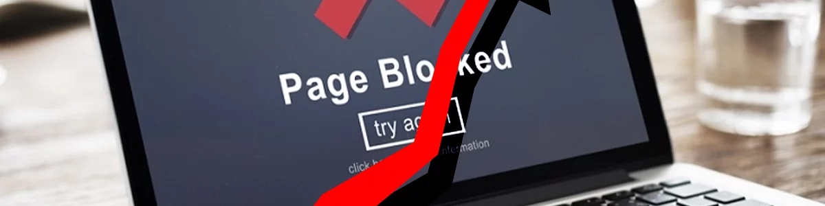 A laptop showing a blocked website page with a red arrow pointing upwards.