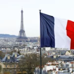 View of the rooftops of paris with the eiffel tower and the french flag.