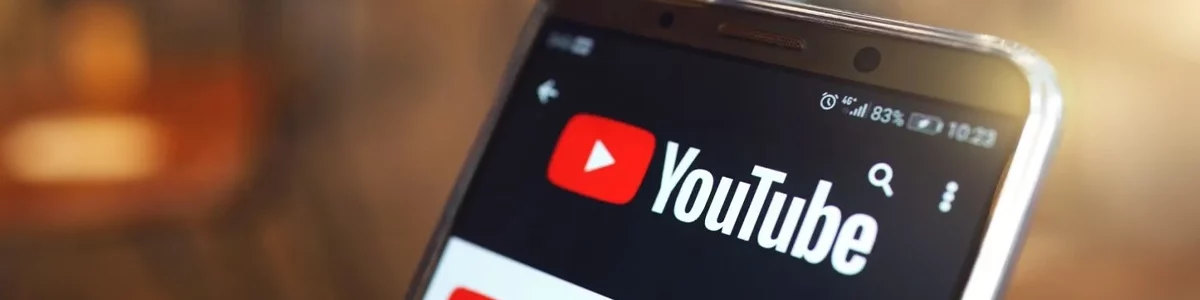 A hand is holding a phone with the youtube app open on the screen